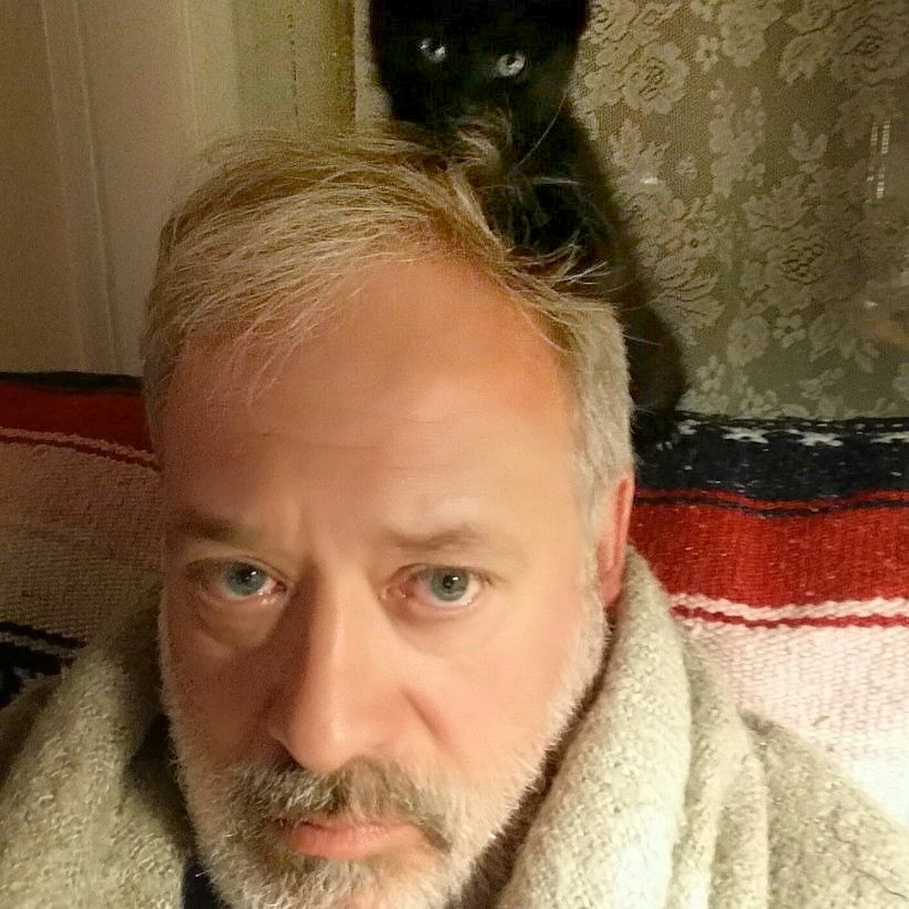 A close selfie of Dr. Smith looking very patient while Hermi the cat perches on top of his head