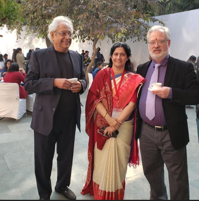 Dr. Smith with two colleagues, holding cups of tea, at a conference in India