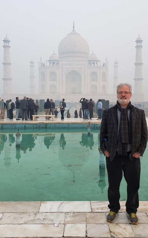 Dr. Smith standing by the reflecting pool in front of the Taj Mahal on a misty morning