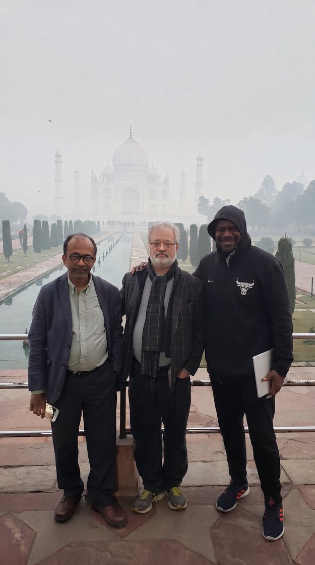 Dr. Smith with two friends in front of the Taj Mahal on a misty morning